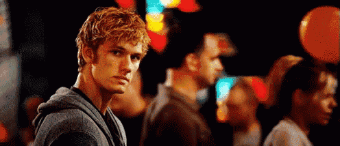 a young man with blonde hair is standing in a crowd of people at night .