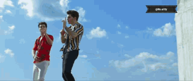 two men are dancing in front of a blue sky