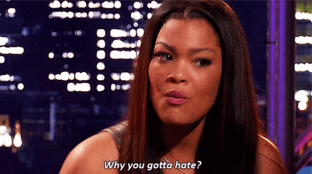 a woman says why you gotta hate in front of a city skyline .