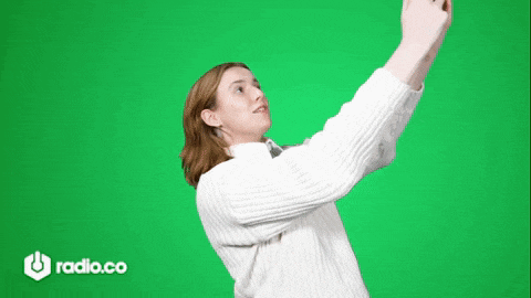 a woman in a white sweater is taking a selfie on a green screen