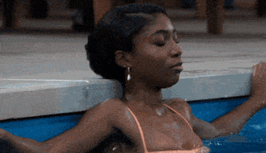a woman in a bathing suit is laying in a pool with her eyes closed
