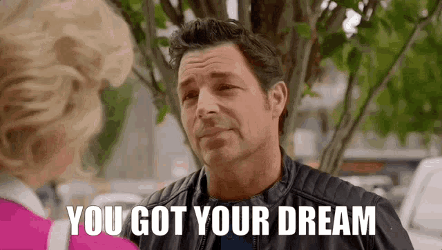 a man in a leather jacket is talking to a woman in a pink shirt and saying `` you got your dream '' .
