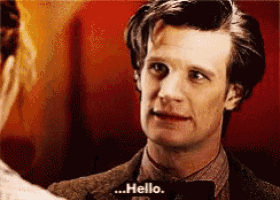 a man in a suit and bow tie is talking to a woman and says hello
