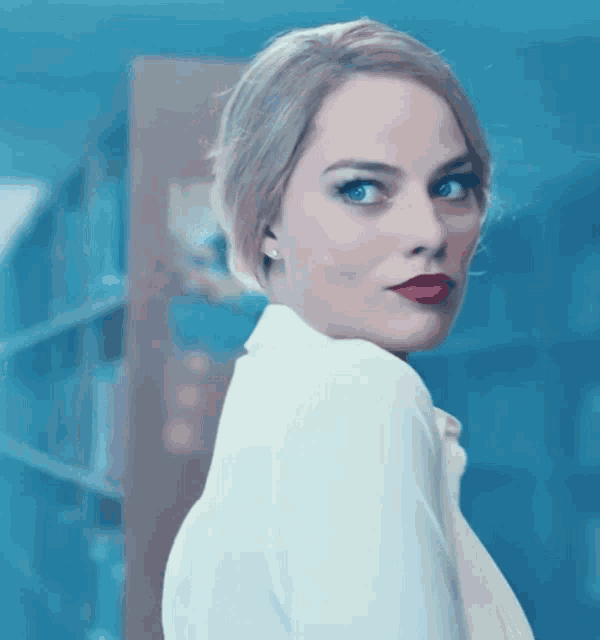 a woman with blonde hair and red lipstick is looking over her shoulder