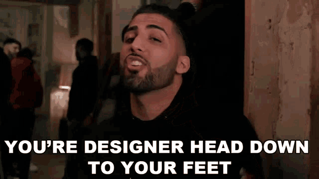 a man with a beard is saying " you 're designer head down to your feet " .