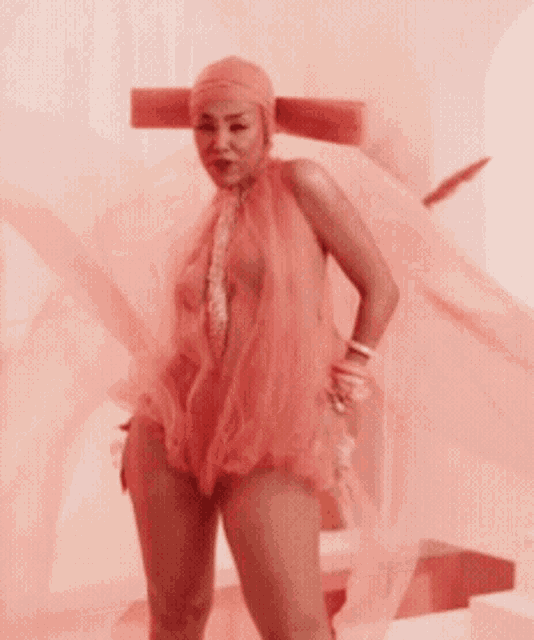 a woman in a pink bodysuit is standing in front of a wall