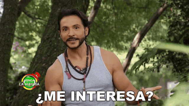 a man in a gray tank top stands in front of a sign that says venga la alegria
