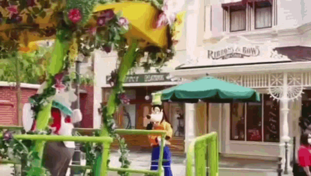 goofy is standing in front of a building with an umbrella in front of it .