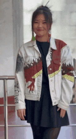 a woman wearing a denim jacket with a picture of a dragon on it .