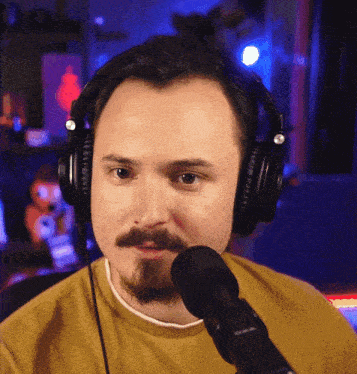 a man wearing headphones and a yellow shirt is speaking into a microphone