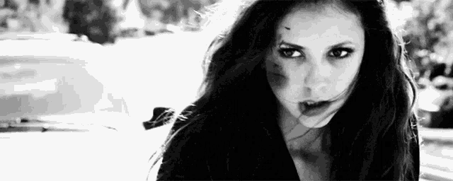 a black and white photo of a woman with a bloody face standing next to a car .