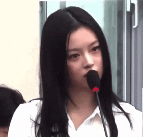 a woman is speaking into a microphone in front of a group of people .