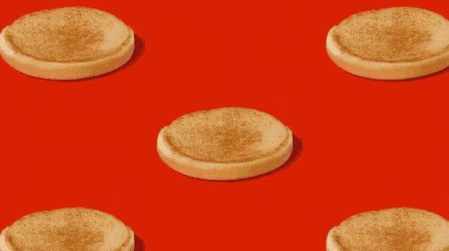a bunch of hamburgers on a red background with sesame seed buns