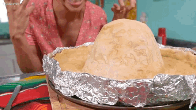 a woman in a pink shirt is looking at a sombrero shaped pie