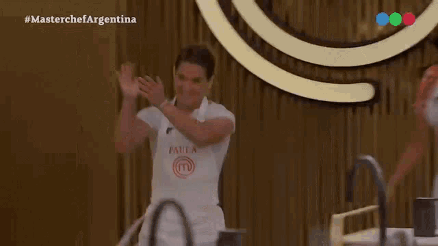 a woman wearing an apron that says masterchef argentina is dancing