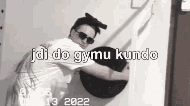 a man wearing sunglasses and a white shirt with the words jdi do gymu kundo written on it