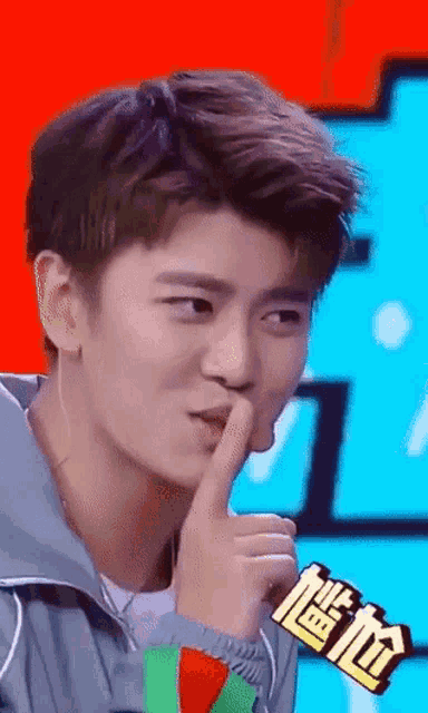 a young man is making a funny face with his finger in his mouth .
