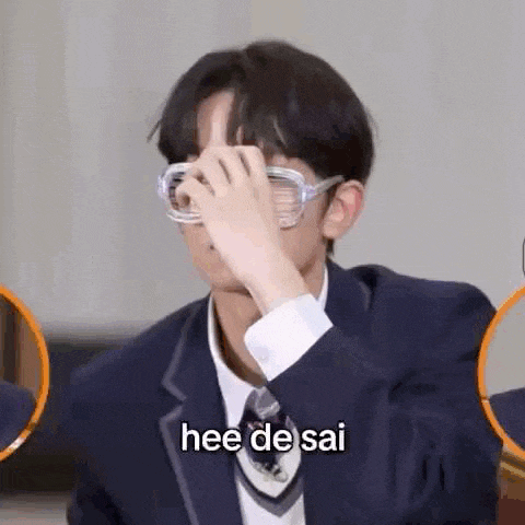 a boy in a suit and tie is covering his face with his hand .