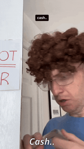 a man with curly hair and glasses is holding a dollar bill and says cash