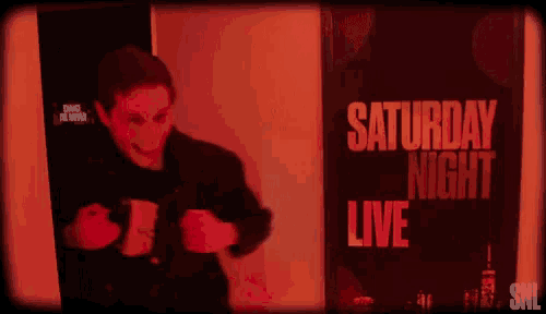 a man is standing in front of a sign that says saturday night live