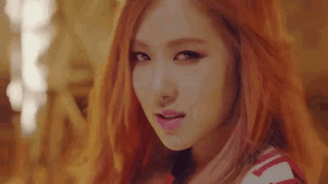 a close up of a woman 's face with red hair and pink lips .