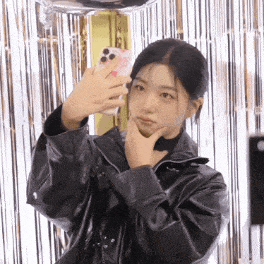 a woman in a leather jacket is taking a picture of herself with her phone