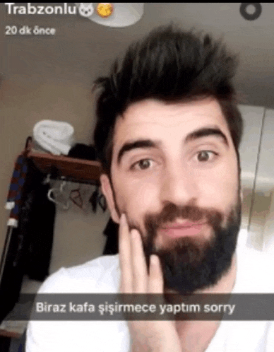 a man with a beard is wearing a white shirt and says biraz kafa isirmece yaptim sorry