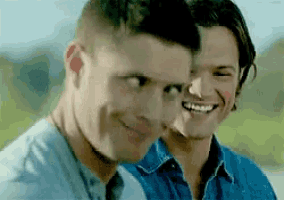 two men are smiling and looking at each other .