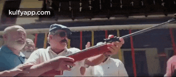 a group of men are standing around a man holding a shotgun .