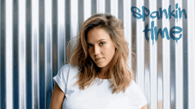 a woman is standing in front of a metal wall with spankin time written on it