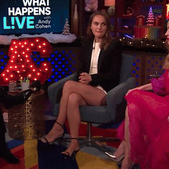 a woman sits in a chair with her legs crossed in front of a sign that says " what happens live "