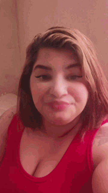 a woman in a red tank top is smiling and making a face