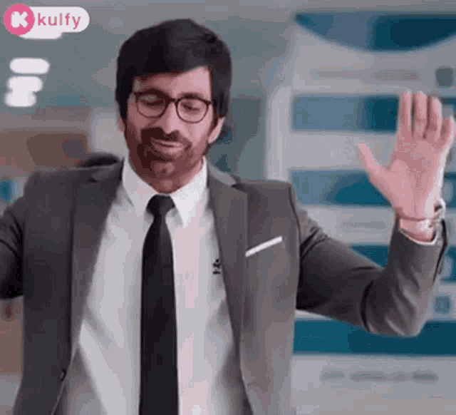 a man in a suit and tie is waving his hand in a room .