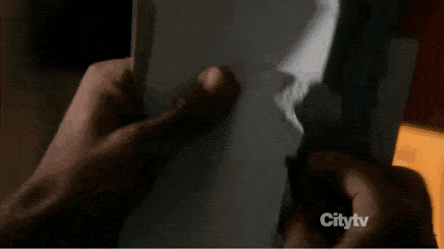 a person is holding a piece of paper in front of a citytv sign