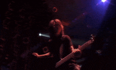 a man singing into a microphone while playing a guitar on stage
