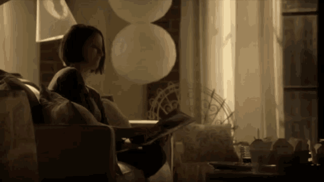a woman is sitting on a couch reading a magazine