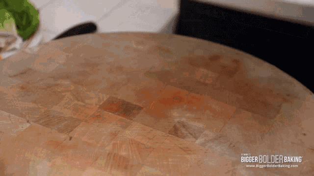 a wooden cutting board with the words bigger bolder baking written on it