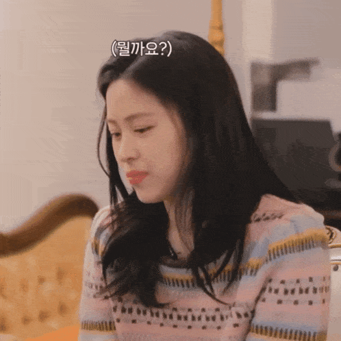 a woman in a striped sweater is sitting on a couch and making a face
