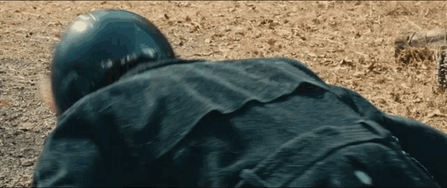 a person wearing a helmet and a black jacket is laying on the ground