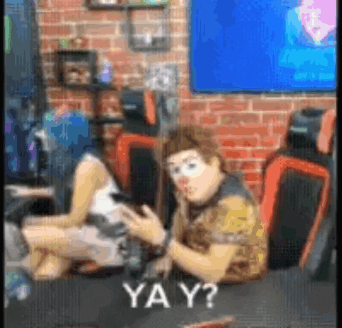 a man and a woman are sitting at a table in a room . the man is wearing a clown mask .