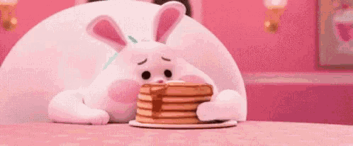 a stuffed bunny is eating a stack of pancakes .