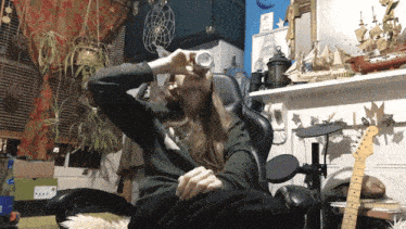 a woman sits in a chair drinking from a can