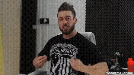 a man with a beard wearing a black shirt is sitting in a chair and making a funny face .
