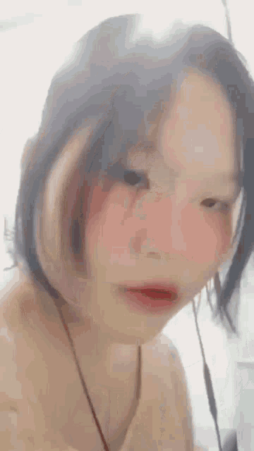 a close up of a girl 's face with pink cheeks and a necklace around her neck .