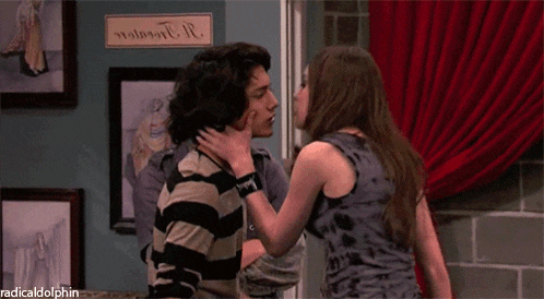 a man and a woman are kissing in front of a sign that says radical dolphin