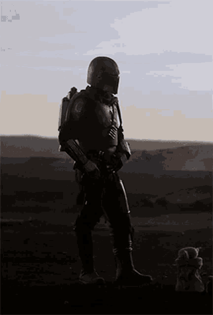 a silhouette of a man in a helmet standing in a desert