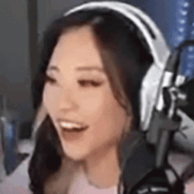 a woman wearing headphones and a microphone is laughing .