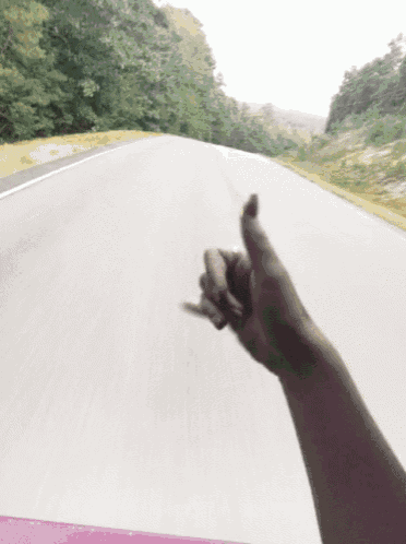 a person 's hand is pointing down a highway