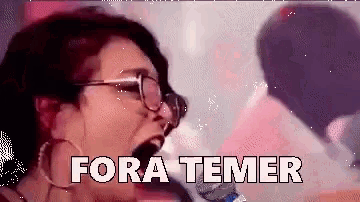 a woman with glasses is singing into a microphone and the words fora temer are visible