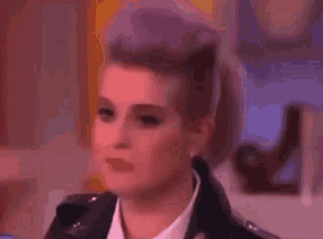 a close up of a woman 's face with purple hair and a black jacket .